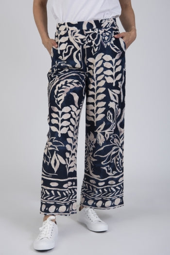 Person wearing navy blue and white patterned trousers on a white background